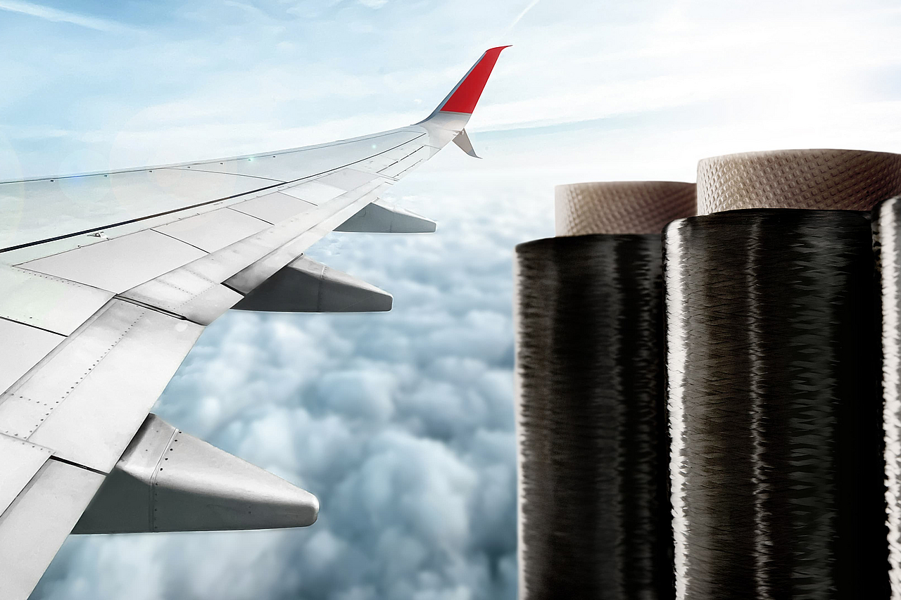 Spulen mit schwarzer Teijin Carbonfaser neben einem Flugzeugflügel über den Wolken, das die Anwendung in der Luftfahrt zeigt.